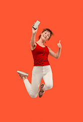 Image showing Full length of pretty young woman with mobile phone while jumping