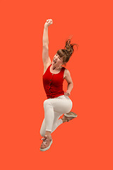 Image showing Freedom in moving. Pretty young woman jumping against orange background