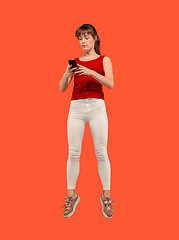 Image showing Full length of pretty young woman with mobile phone while jumping