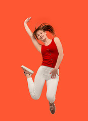 Image showing Freedom in moving. Pretty young woman jumping against orange background