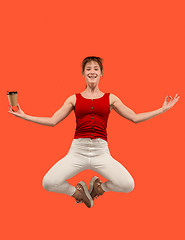 Image showing Freedom in moving. Pretty young woman jumping against orange background