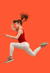 Image showing Freedom in moving. Pretty young woman jumping against orange background