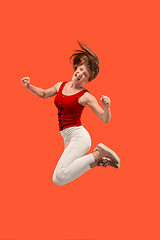 Image showing Freedom in moving. Pretty young woman jumping against orange background