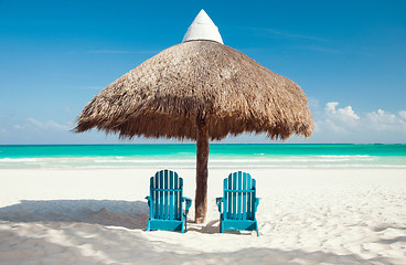 Image showing two sun chairs under palapa on tropical beach