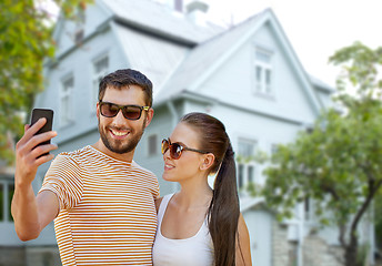 Image showing couple taking selfie by smartphone over house