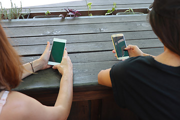 Image showing Two young girls watching smart mobile phones