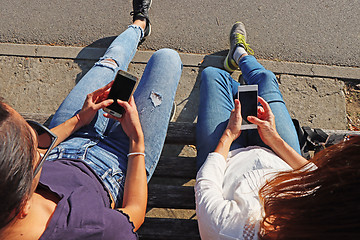 Image showing Two young girls watching smart mobile phones