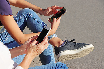Image showing Two young girls watching smart mobile phones