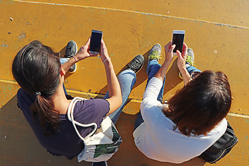 Image showing Two young girls watching smart mobile phones