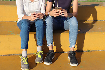 Image showing Two young girls watching smart mobile phones