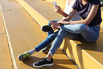 Image showing Two young girls watching smart mobile phones