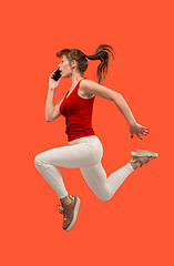 Image showing Full length of pretty young woman with mobile phone while jumping