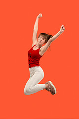 Image showing Freedom in moving. Pretty young woman jumping against orange background