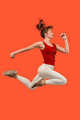 Image showing Freedom in moving. Pretty young woman jumping against orange background