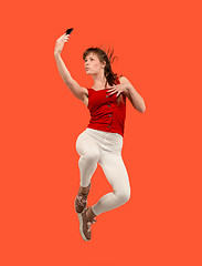 Image showing Full length of pretty young woman with mobile phone while jumping