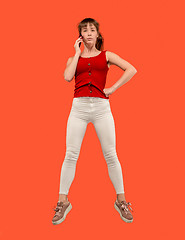 Image showing Full length of pretty young woman with mobile phone while jumping