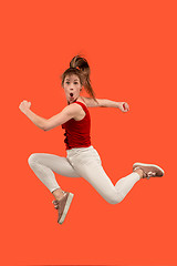 Image showing Freedom in moving. Pretty young woman jumping against orange background