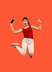 Image showing Full length of pretty young woman with mobile phone while jumping