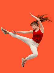 Image showing Freedom in moving. Pretty young woman jumping against orange background