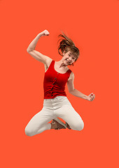 Image showing Freedom in moving. Pretty young woman jumping against orange background