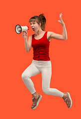 Image showing Beautiful young woman jumping with megaphone isolated over red background