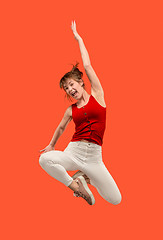 Image showing Freedom in moving. Pretty young woman jumping against orange background