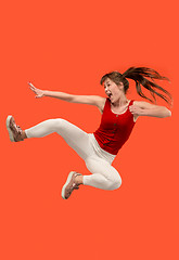 Image showing Freedom in moving. Pretty young woman jumping against orange background