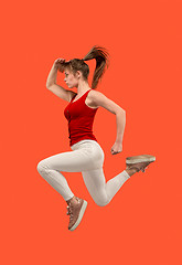 Image showing Freedom in moving. Pretty young woman jumping against orange background