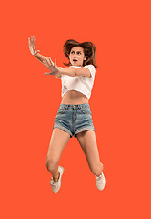 Image showing Freedom in moving. Pretty young woman jumping against orange background