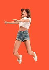 Image showing Freedom in moving. Pretty young woman jumping against orange background