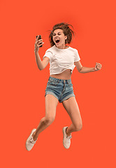 Image showing Full length of pretty young woman with mobile phone while jumping