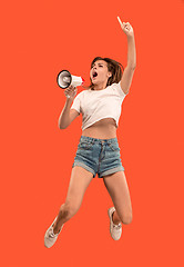 Image showing Beautiful young woman jumping with megaphone isolated over red background