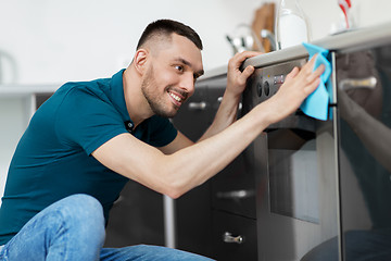 Image showing man with rag cleaning oven door at home kitchen