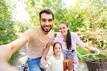 Image showing happy family with bicycles taking selfie in summer