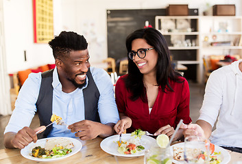 Image showing happy friends eating and talking at restaurant