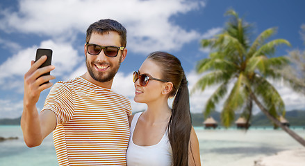 Image showing happy couple taking selfie by smartphone on beach