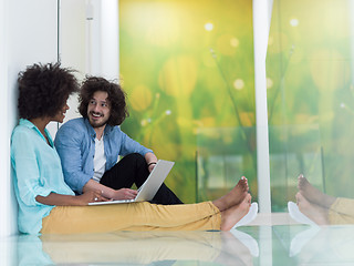 Image showing multiethnic couple using a laptop on the floor