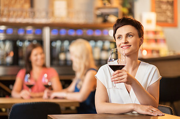 Image showing happy woman drinking red wine at bar or restaurant