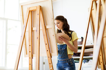 Image showing student girl with easel painting at art school