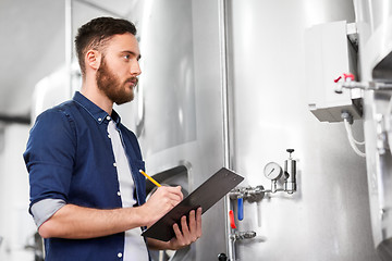 Image showing man with clipboard at craft brewery or beer plant