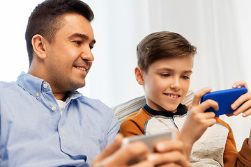 Image showing happy father and son with smartphones at home