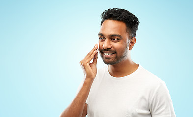 Image showing smiling indian man cleaning face with cotton pad