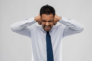 Image showing screaming businessman covering ears with hands