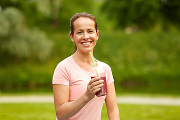 Image showing woman drinking smoothie after exercising in park