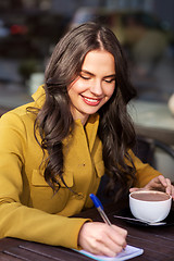 Image showing happy woman with notebook drinking cocoa at cafe