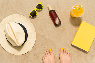 Image showing feet, hat, shades, sunscreen and juice on beach