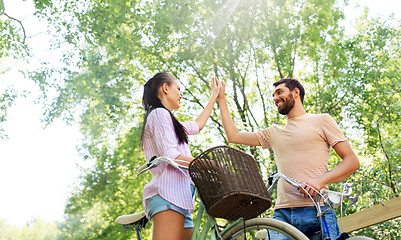 Image showing couple with bicycles making high five in summer