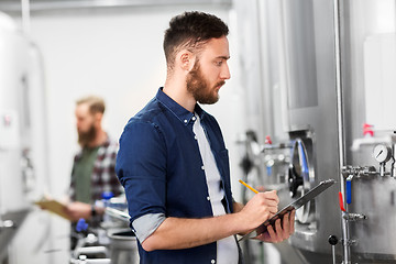 Image showing man with clipboard at craft brewery or beer plant