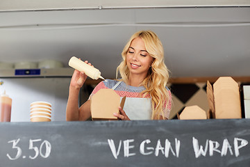 Image showing happy saleswoman making wok at food truck