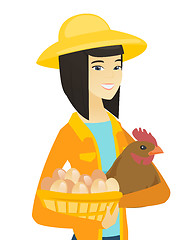 Image showing Asian farmer holding chicken and basket of eggs.